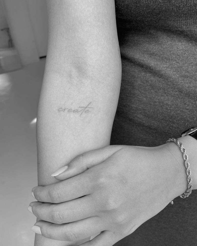Tattoo of the word "create" located on the inner forearm.