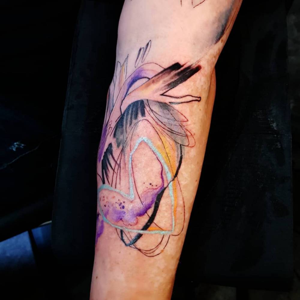 Abstract heart tattooed on the inner forearm, watercolor style.