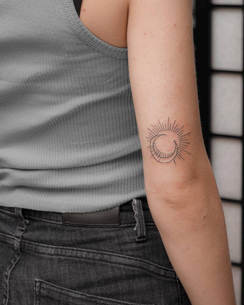 Fine line sun and moon tattoo located on the tricep.
