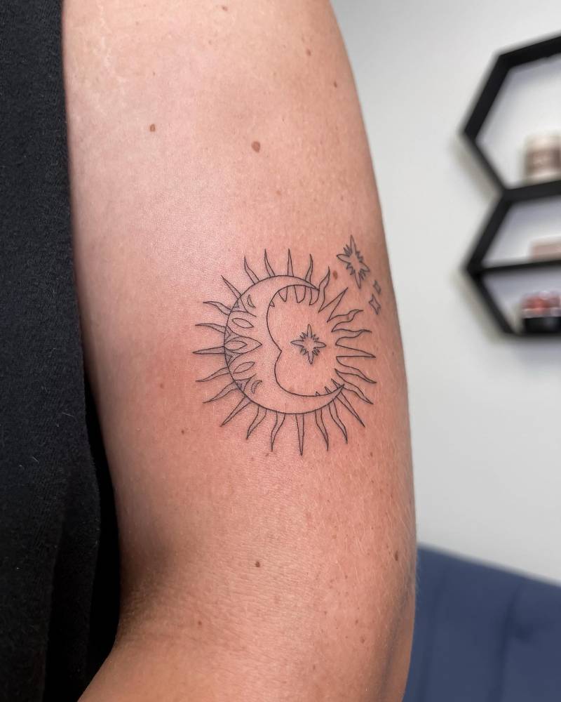Ornamental sun and moon tattoo placed on the upper arm, fine line style.