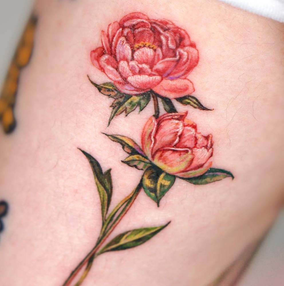 Pink peonies tattooed on the inner arm, done in watercolor style.