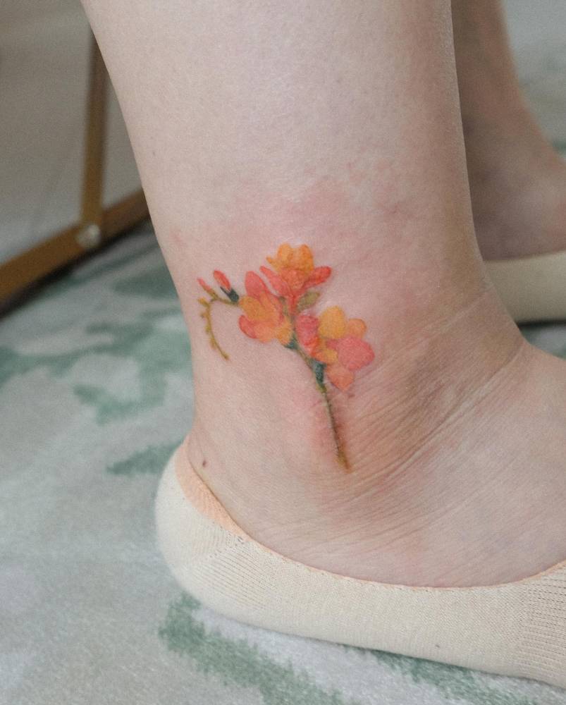 Scar cover-up freesia tattoo on the ankle.