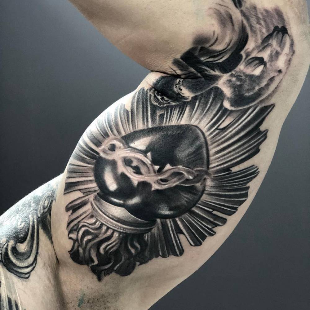 Black and grey sacred heart tattoo on the inner arm.