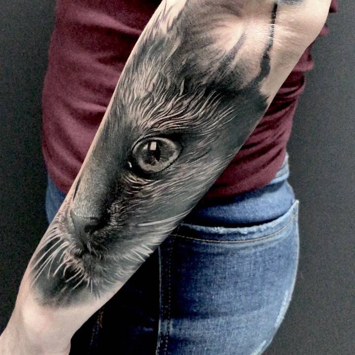 Black and grey cat portrait tattoo on the forearm.