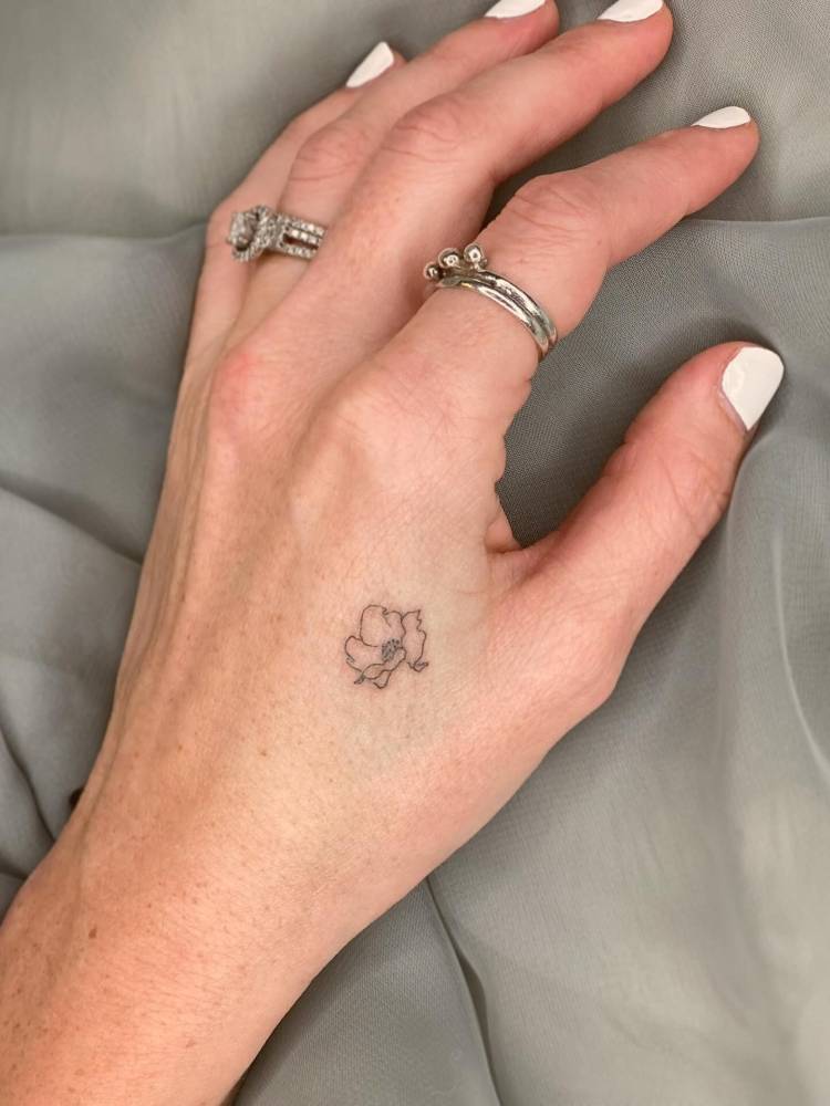Minimalistic little poppy flower tattoo located on the hand.