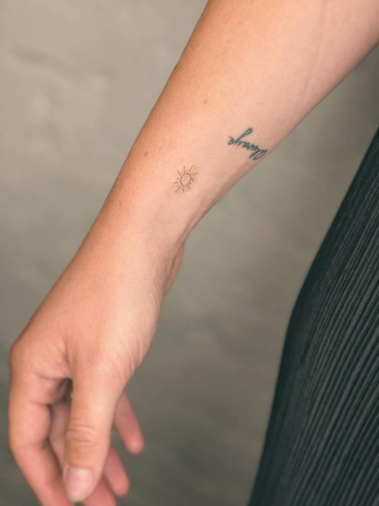 Tiny minimalistic sun tattooed on the wrist.
