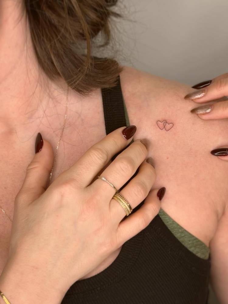 Minimalistic heart couple tattoo located on the shoulder.