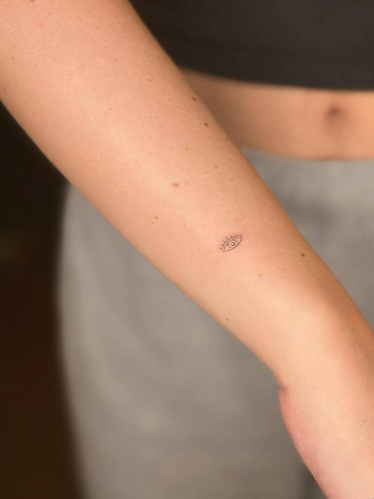 Tiny eye tattoo in minimalistic style done on the wrist.