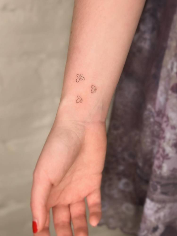 Tiny minimalistic butterflies tattooed on the wrist.