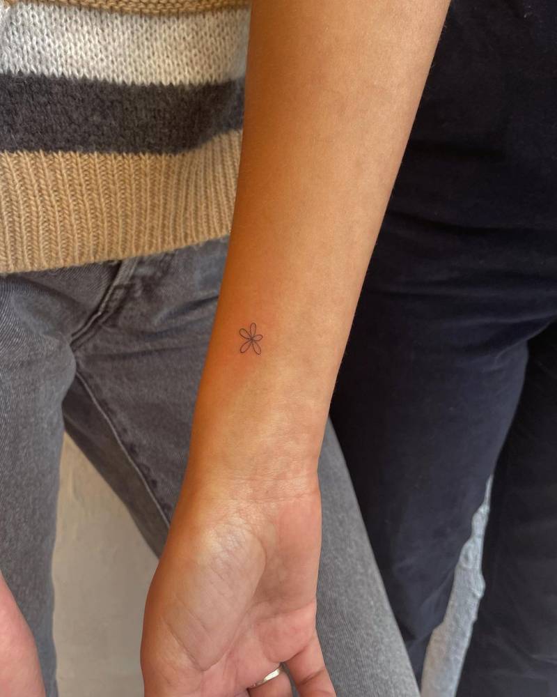 Tiny minimalistic flower tattoo located on the wrist.