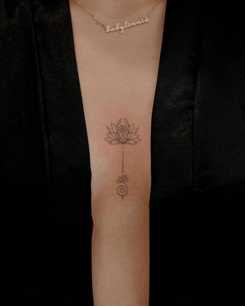 Fine line style lotus unalome tattoo located on the sternum.
