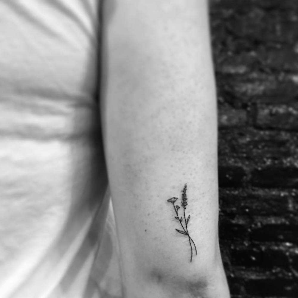 Fine line flower tattoo located on the tricep.