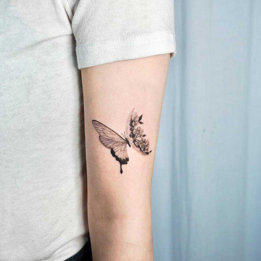 Half butterfly half flower tattoo located on the upper arm.