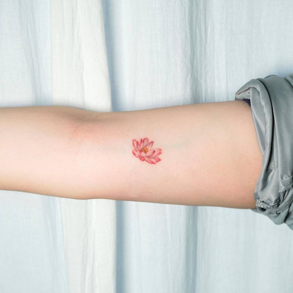 Micro-realistic style lotus flower tattoo located on the inner arm.