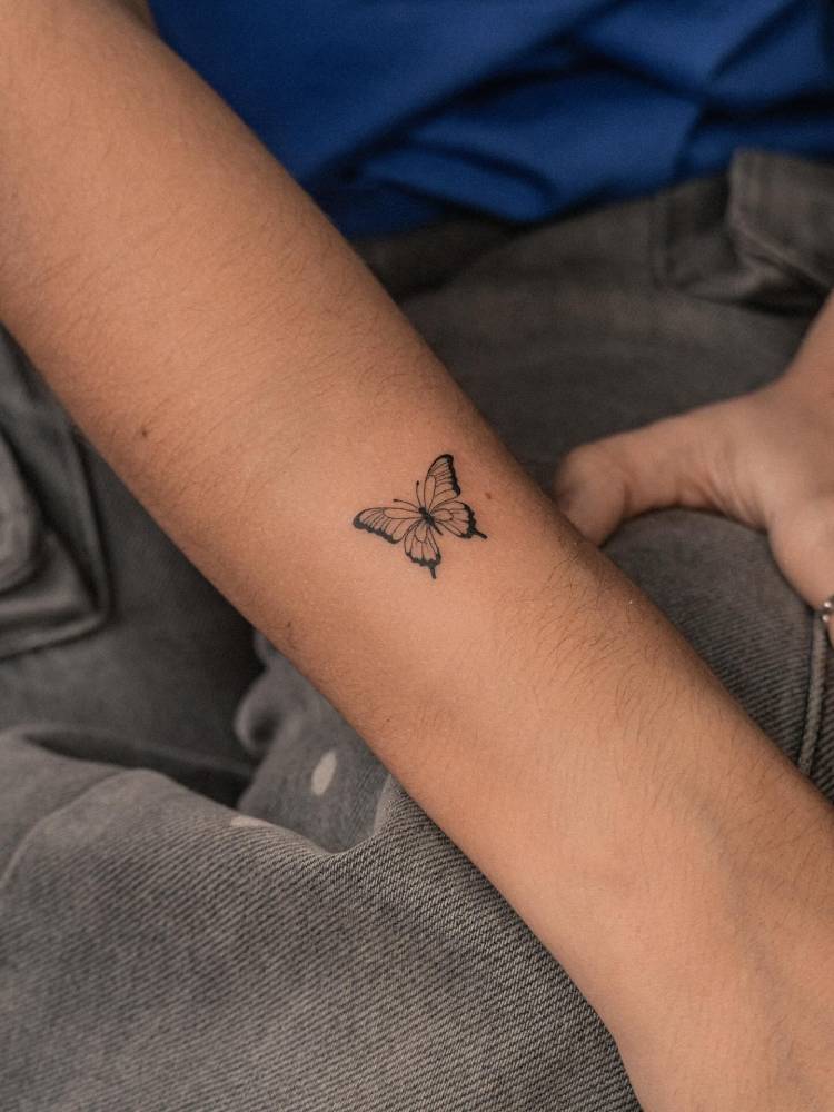 Illustrative style butterfly tattoo located on the forearm.