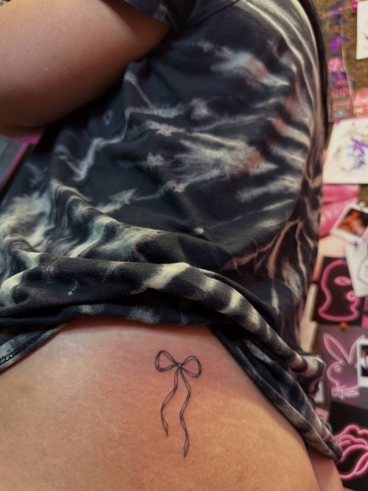 Bow tattoo in illustrative style located on the butt cheek.