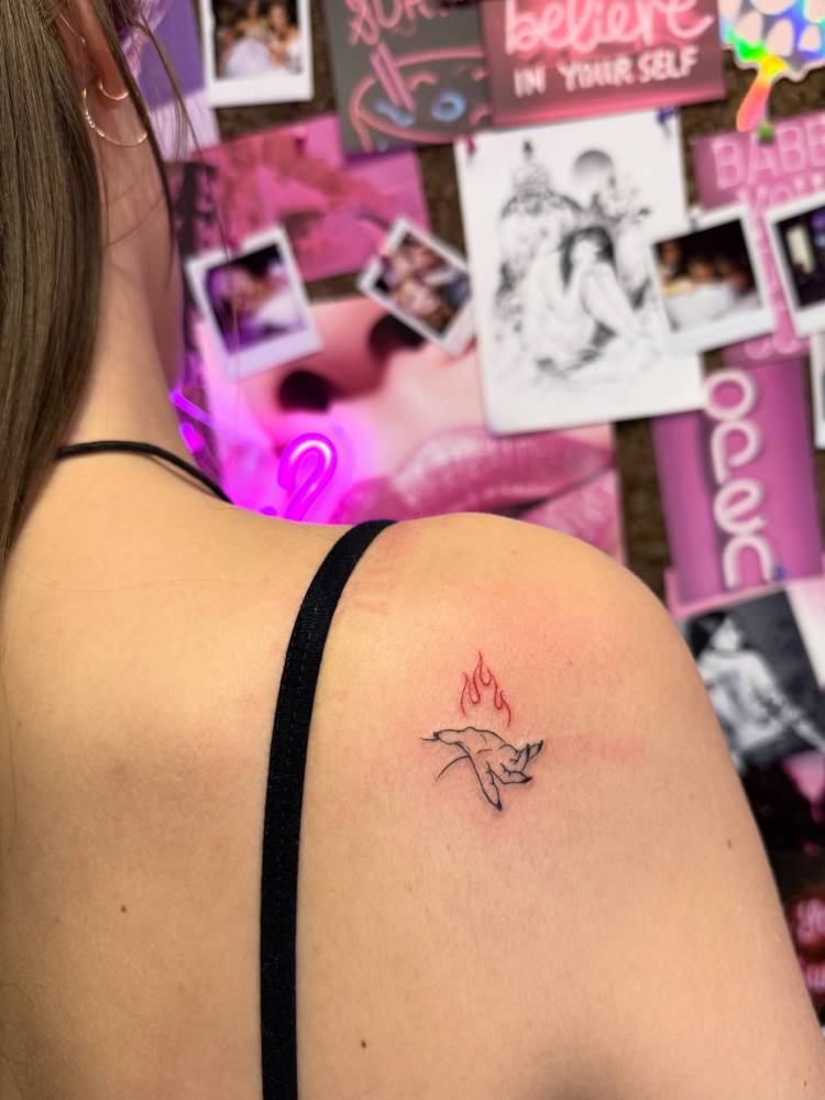 Hand holding fire tattoo located on the shoulder blade.