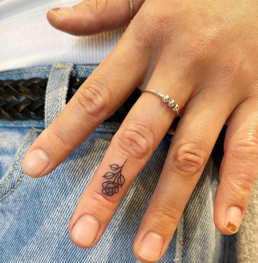 Tiny minimalistic rose tattoo located on the finger.