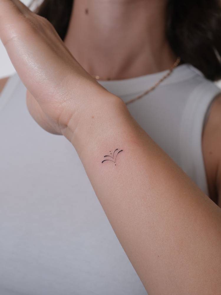 Minimalistic style ornament tattoo located on the wrist.