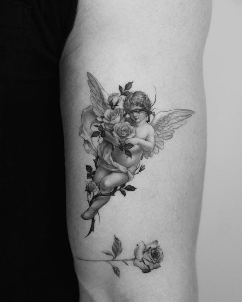 Micro-realistic style cherub tattoo located on the upper arm.