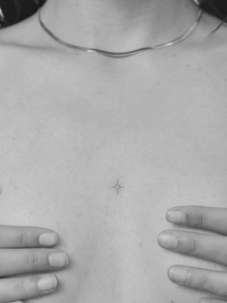 Tiny minimalistic north star tattoo placed on the sternum.