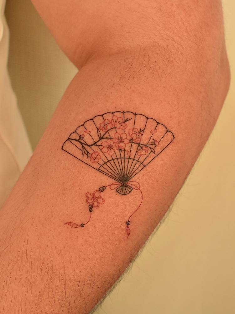 Cherry blossom hand fan tattoo located on the forearm, fine line style.