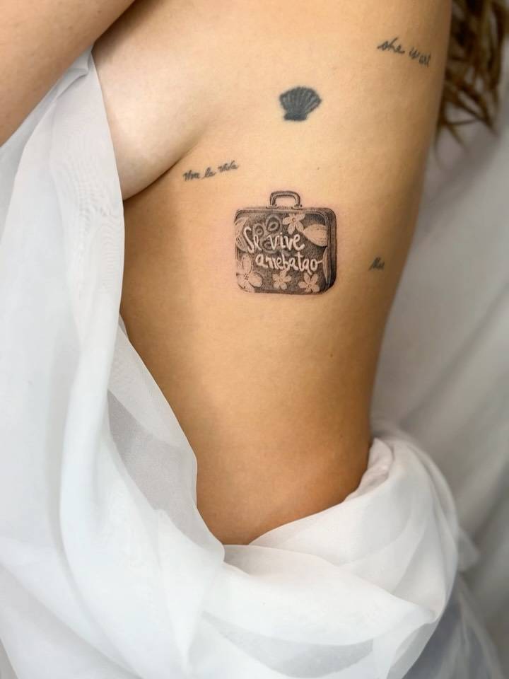 Little suitcase tattoo in micro-realistic style located on the rib.