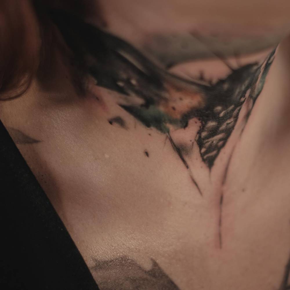 Watercolor style moth tattoo located on the neck.