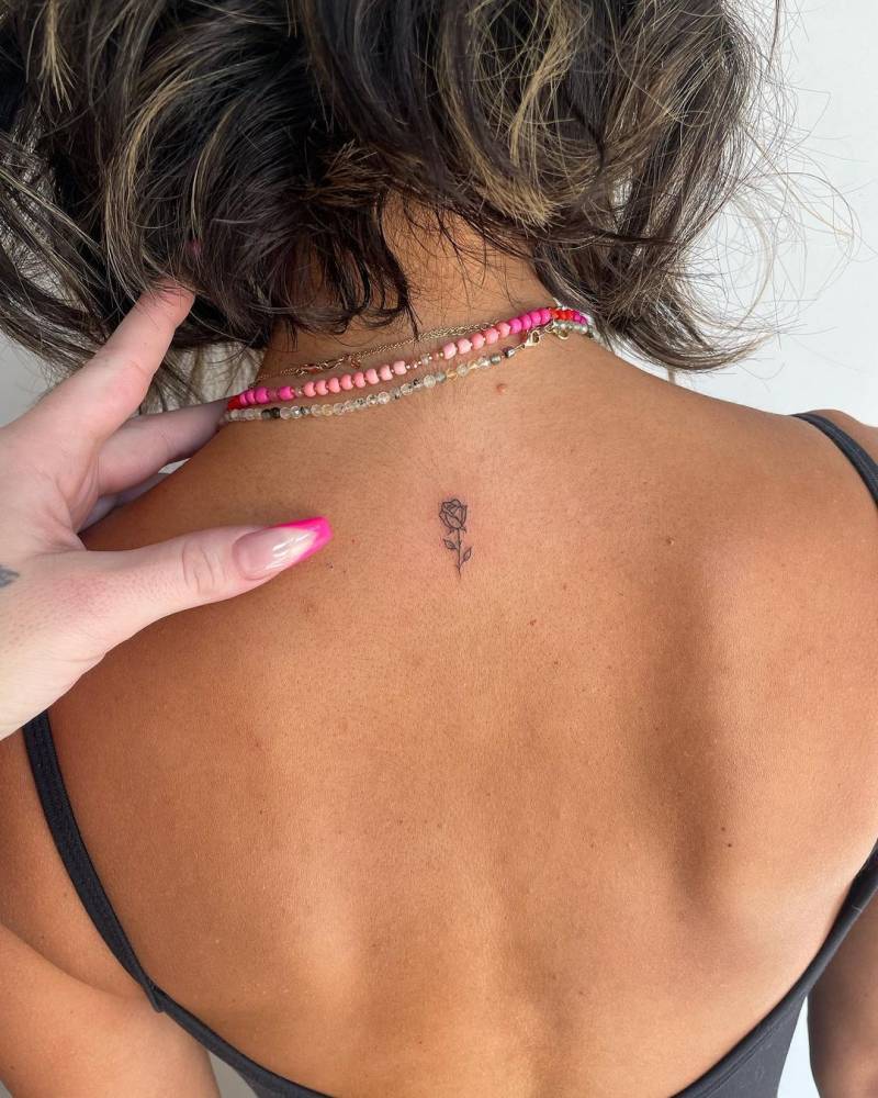 Tiny minimalistic rose tattoo located on the upper back.