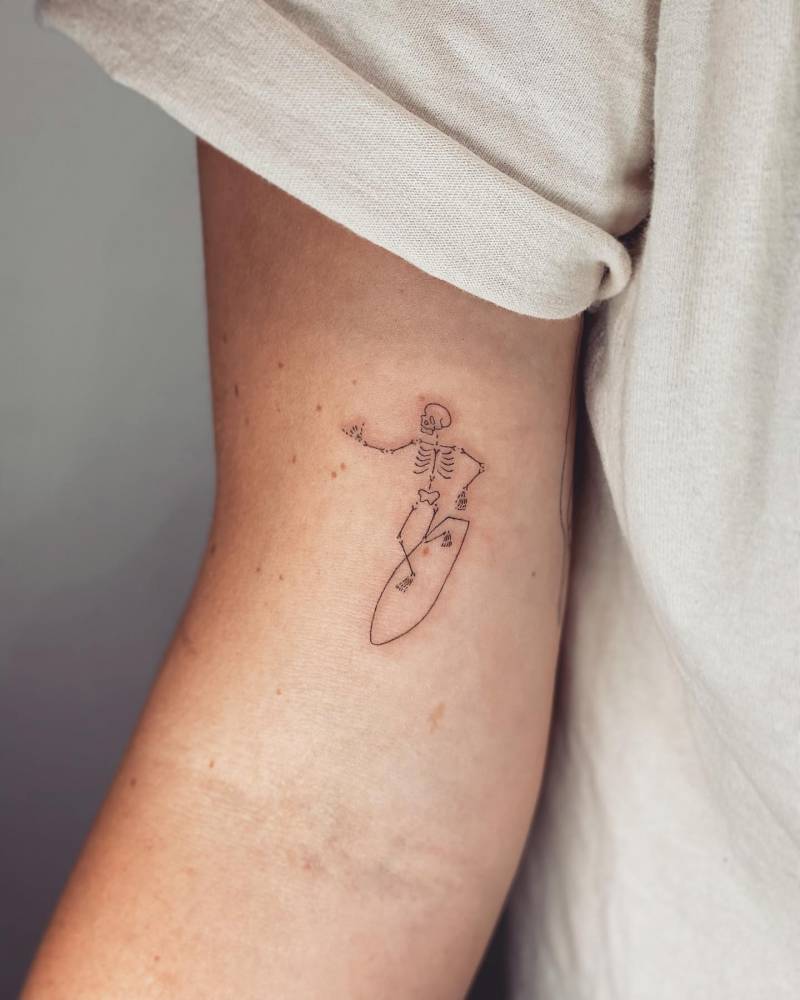 Fine line style surfing skeleton tattoo done on the inner arm.