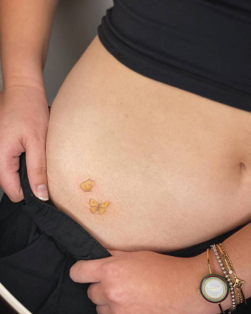 Yellow butterfly couple tattoo located on the hip, illustrative style.