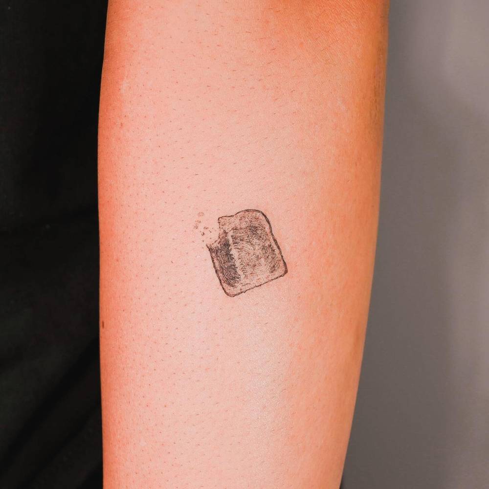 Toast tattoo located on the forearm, micro-realistic style.