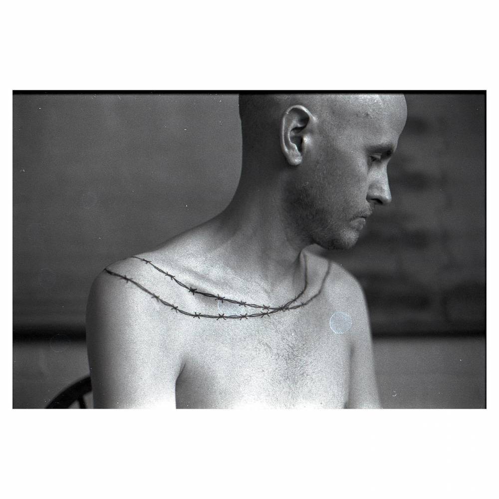 Barbed wire tattoo located around the shoulders.