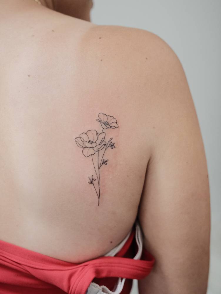 Poppy flowers tattoo in fine line style located on the shoulder blade.
