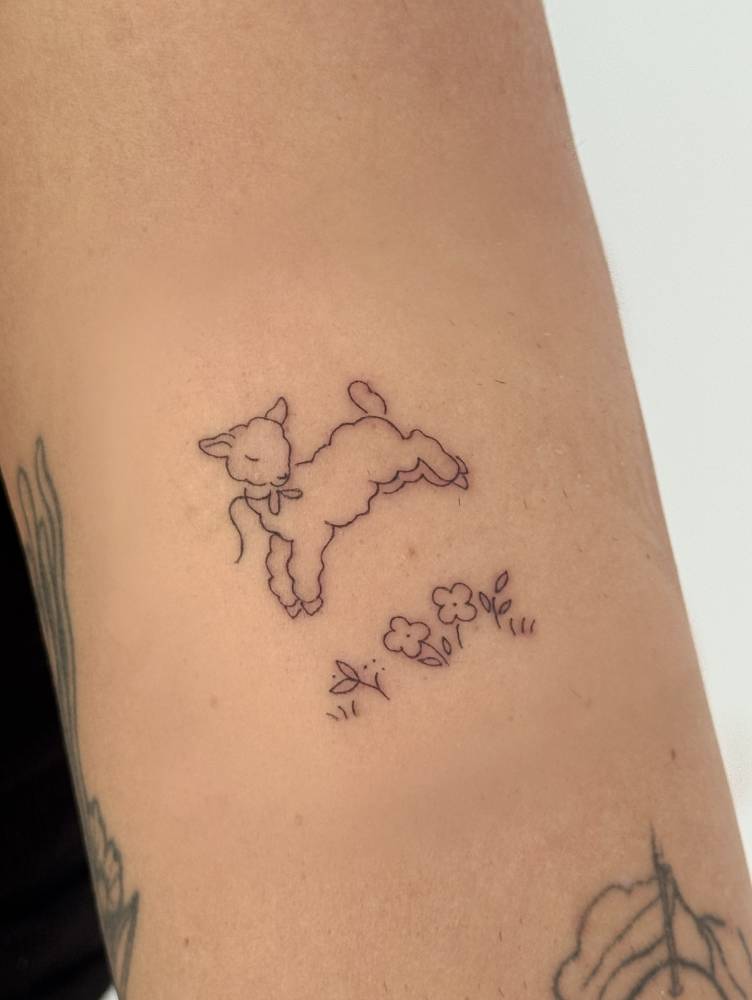 Cute lamb tattoo in fine line stye done on the upper arm.