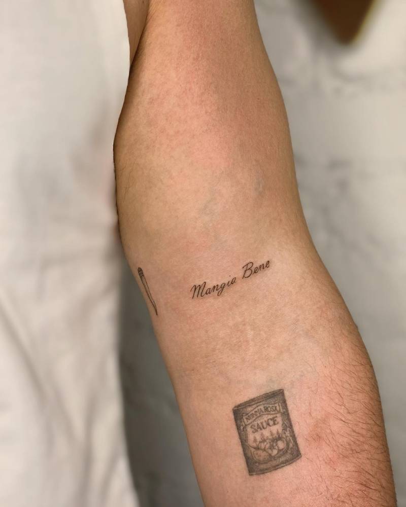 "Mangia bene" lettering tattoo located on the bicep.