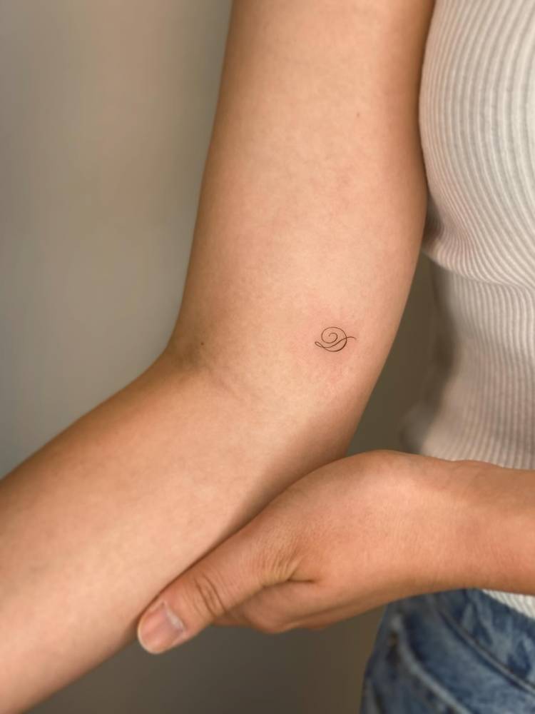 Script font letter "D" tattoo located on the inner arm.
