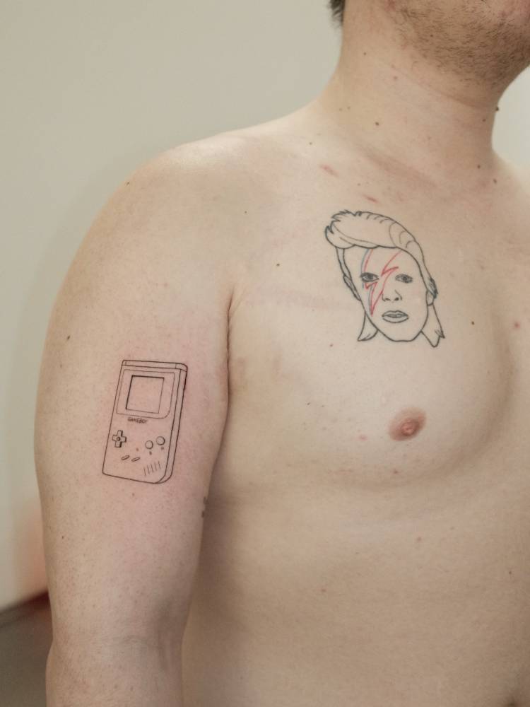 Game Boy tattoo in illustrative style located on the upper arm.