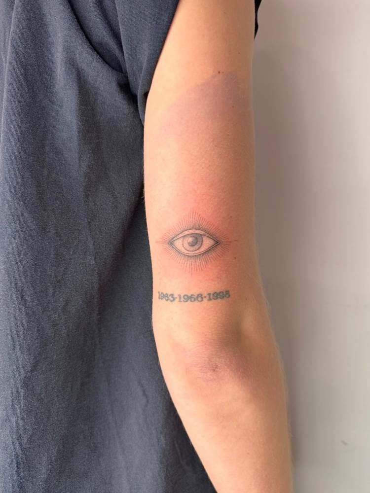Evil eye tattoo in illustrative style located on the tricep.