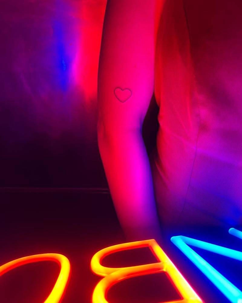 Minimalistic heart tattoo located on the upper arm.