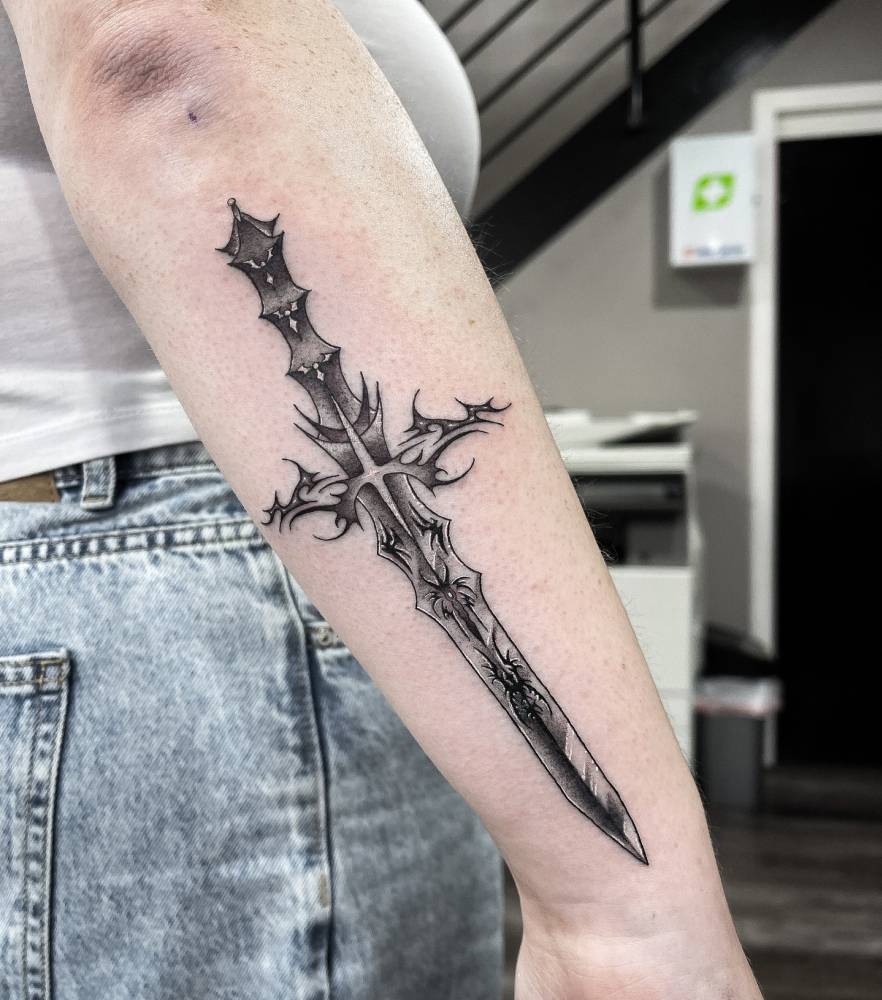 Dagger tattoo in illustrative style placed on the forearm.