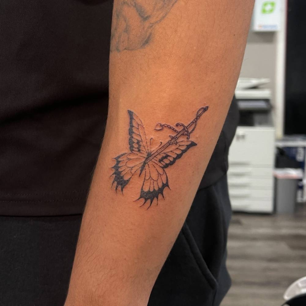 Butterfly and sword tattoo placed on the forearm, illustrative style.