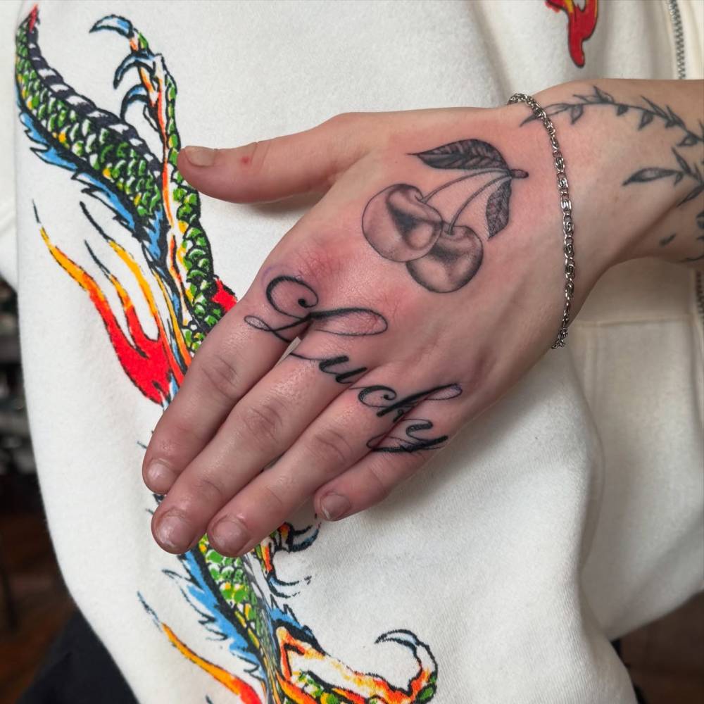 Lettering tattoo of the word "lucky" located on the fingers.