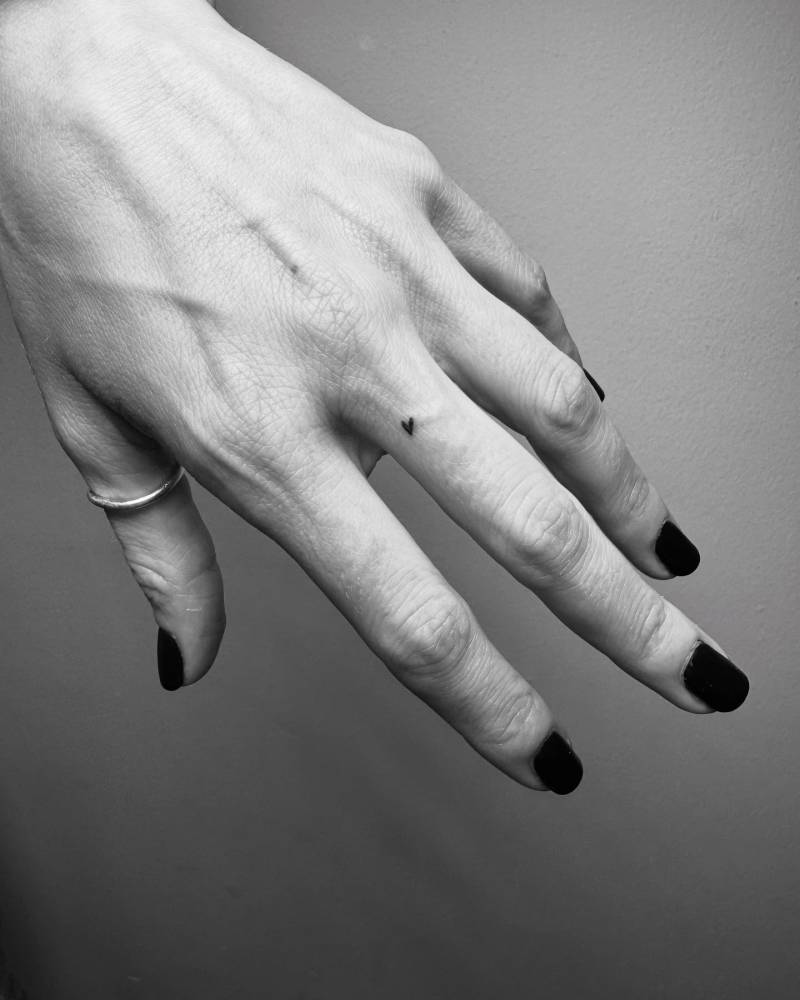 Micro heart in minimalistic style tattooed on the finger.