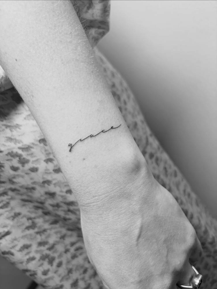Handwritten font word "grace" tattoo done on the wrist.