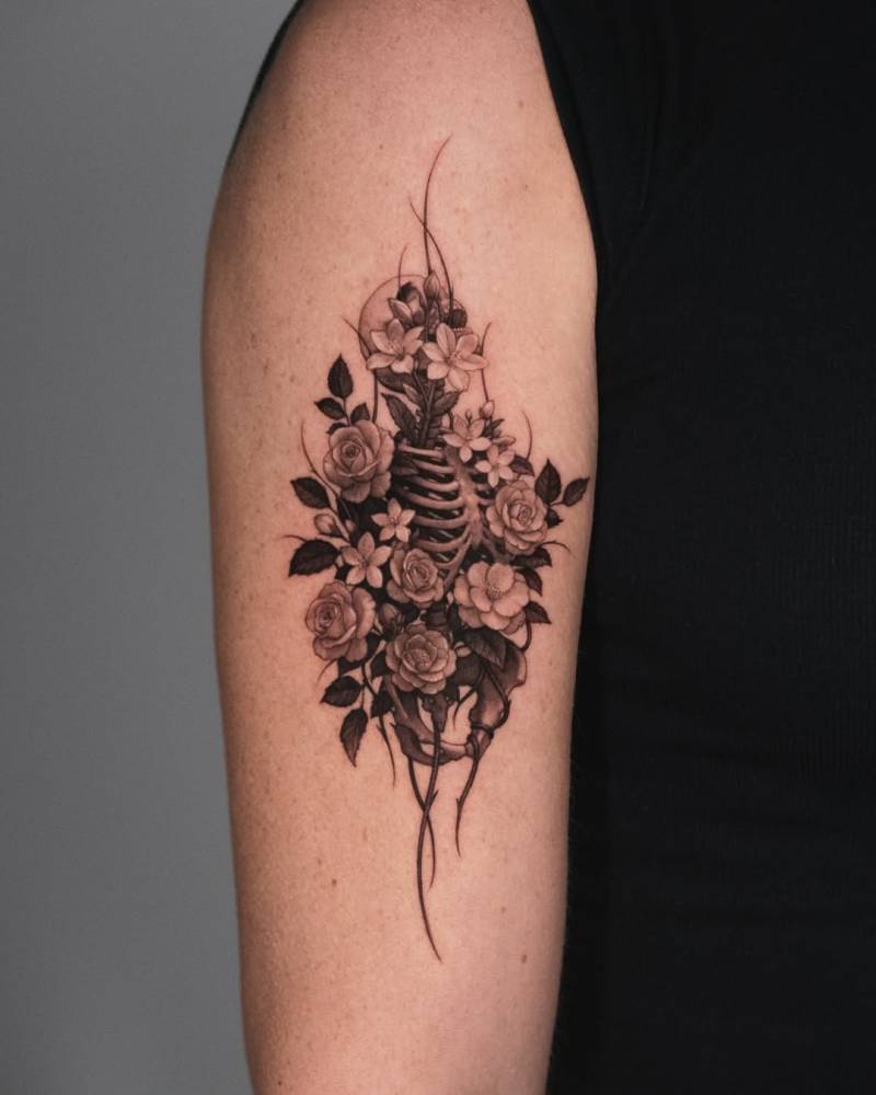 Skeleton and flowers in micro-realism tattooed on the upper arm.