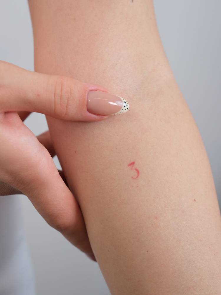 Tiny number "3" in red ink tattooed on the inner forearm.