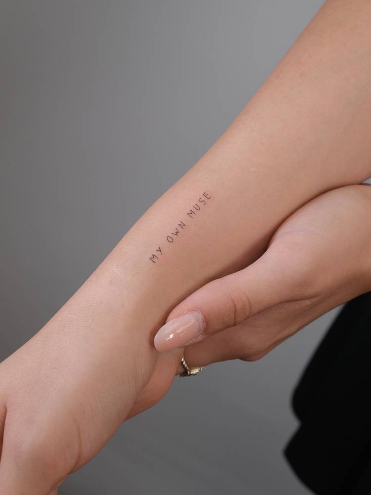 Handwritten font "my own muse" lettering tattoo located on the wrist.