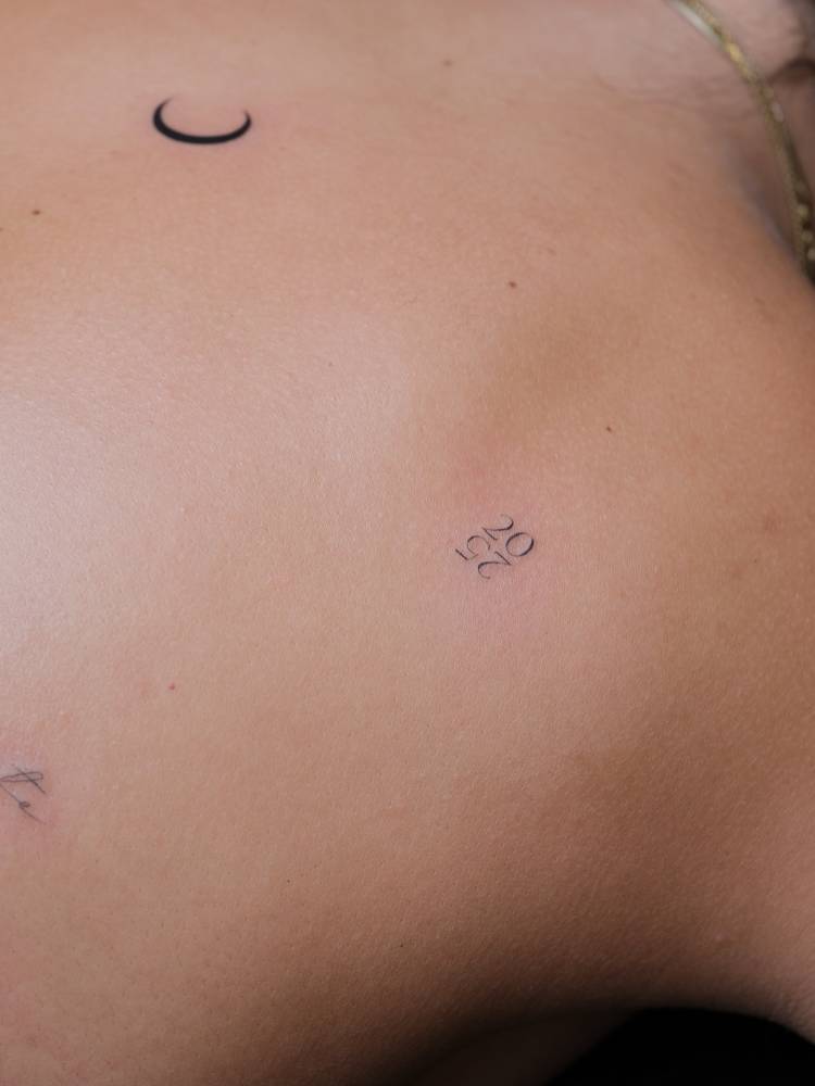 "2025" tattoo located on the shoulder blade.