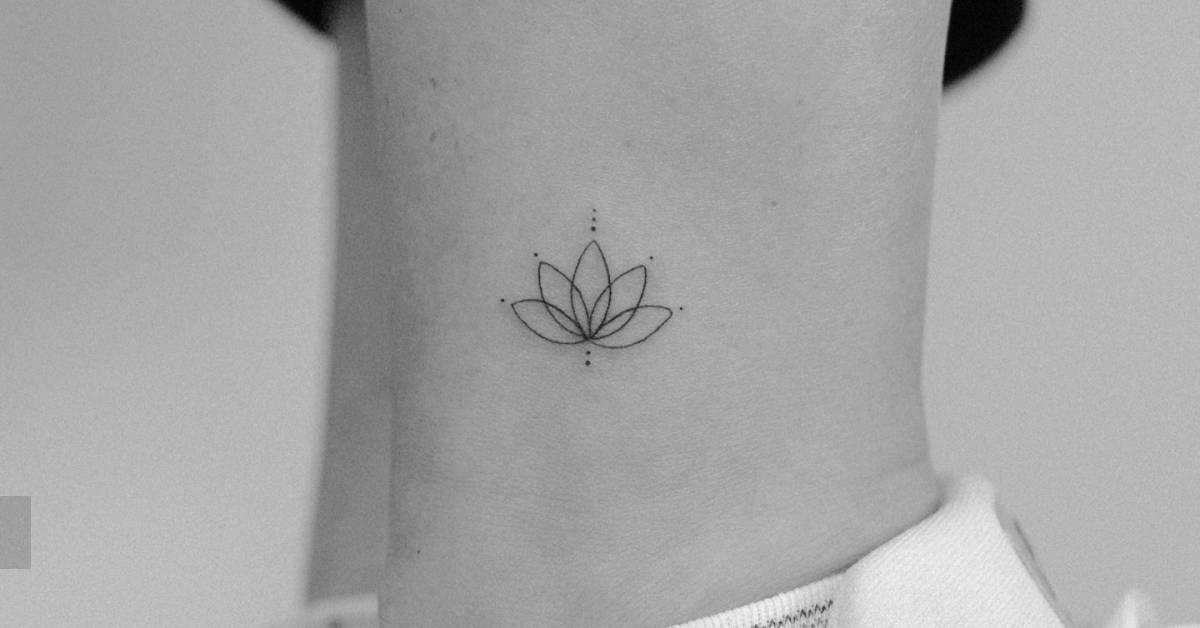 Fine line style little lotus flower tattoo located on